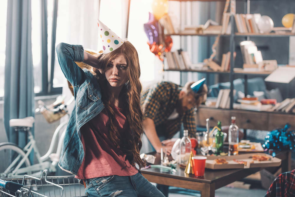 Confused,Woman,In,Birthday,Hat,,Man,Cleaning,Behind,In,Messy